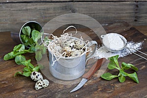 Quail easter eggs in a aluminum cup, green lettuce and flour on wooden table