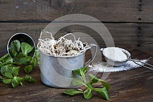 Quail easter eggs in a aluminum cup, green lettuce and flour on wooden table