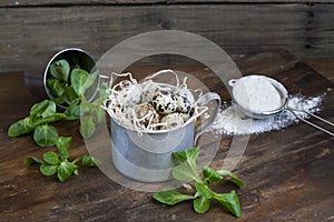 Quail easter eggs in a aluminum cup, green lettuce and flour on wooden table