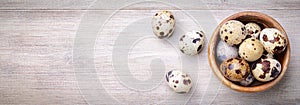 Quail eggs in a bowl on a wooden background, top view, space for text. photo