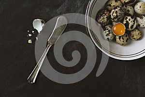 Quail eggs in ceramic bowl on black rustic background