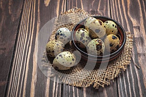 Quail eggs in a clay plate on a dark wooden background