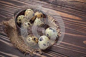 Quail eggs in a clay plate on a dark wooden background
