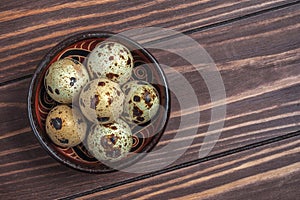 Quail eggs in a clay plate on a wooden background