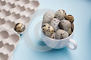 Quail eggs in cup and cardboard packaging on blue background..Vegetarian food concept. Eco products photo