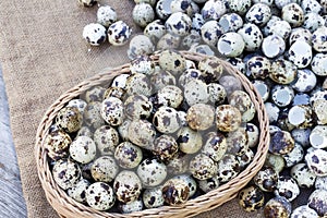 Quail eggs a lot of in basket and heap shell quail eggs on sackcloth of the wooden background