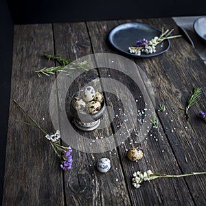 Quail eggs in metal rustic bowl on wooden country table in inter