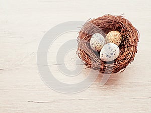 Quail eggs in a nest of branches lying on a wooden background, a postcard for Easter