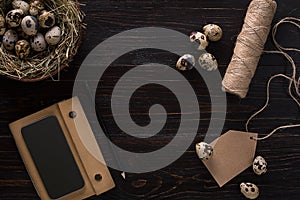 Quail eggs in nest, notebook and thread on a black background
