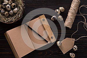 Quail eggs in nest, notebook and thread on a black background