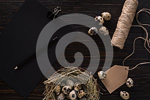 Quail eggs in nest, notebook and thread on a black background