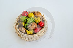 Quail eggs painted in different colors in a light wicker basket