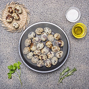 Quail eggs in a pan with oil and salt and herbs granitic rustic background top view close up