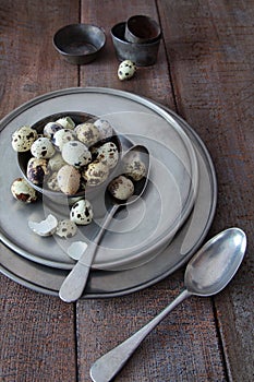 Quail eggs with pewter plates on wood table