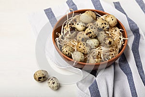 Quail eggs in a plate on an old white wooden background.