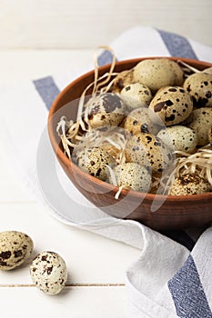 Quail eggs in a plate on an old white wooden background.
