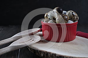 Quail eggs in red pot and kitchen tools.