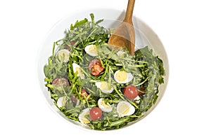 Quail eggs salad in a bowl with a wooden spoon