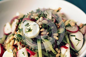 Quail eggs salad in a white bowl. European cuisine