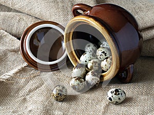 Quail eggs are scattered from a crock pot on coarse cloth