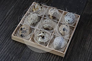 Quail eggs in wooden box on dark background