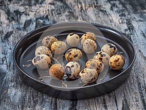 quail eggs in wooden plate over dark wooden background