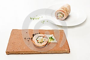 Quail galantine, de-boned stuffed meat as a cold appetizer for a festive dinner, served on a brick stone, white table with copy photo