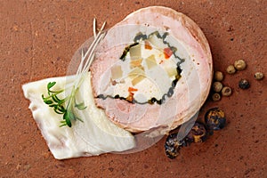 Quail galantine, de-boned stuffed meat for a festive dinner on a rustic brick plate, copy space, high angle view from above photo