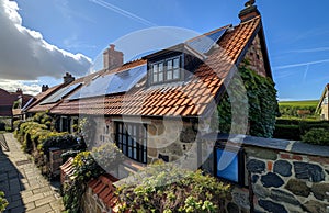 Quaint cottage with solar panels on the roof. A photo of solar panels on the roof of an electric house