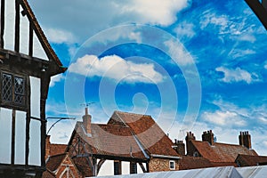 Quaint European village with traditional half-timbered houses and terracotta rooftops under a vibrant blue sky with fluffy clouds