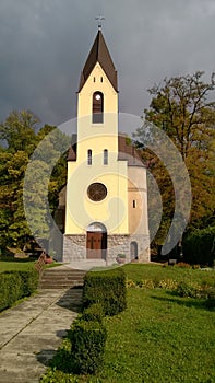 Quaint little country church sitting in a green meadow surrounded by trees in the summer time