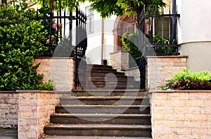 quaint old gray rough stone exterior stair with weathered grunge white stucco walls and green plants in stone planters