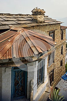 A quaint, old structure with stone walls,chimney roof slanting stone tin roofs  Almora