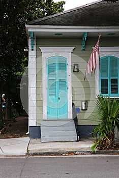 Quaint one story green Creole cottage with white trim and blue shutters, New Orleans.