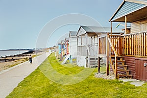 Quaint wooden beach huts in a row along a grass verge