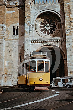 Quaint yellow tram passes directly in front of the Se Cathedral in Lisbon. Lisboa Lissabon