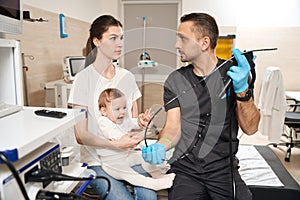 Qualified diagnostician preparing child for endoscopy in female parent presence