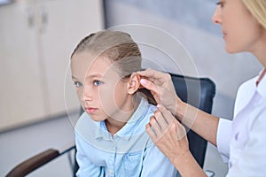 Qualified doctor fixing a deaf aid behind the girls ear