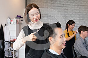 Qualified female barber make haircut for two male customer with male hairstyle.