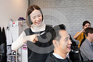 Qualified female barber make haircut for two male customer with male hairstyle.
