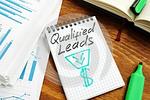 Qualified leads handwritten on a page and business papers