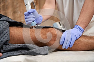 Qualified medic using radiofrequency therapy device on his patient