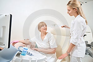 Qualified sonographer explaining to nurse how to do thyroid gland ultrasound