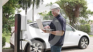 Qualified technician working with laptop for home EV station. Fastidious