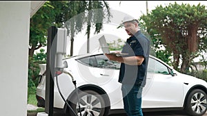 Qualified technician working with laptop for home EV station. Fastidious
