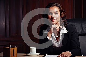 Qualified to give expert advice. Attractive mature legal woman sitting and leaning on her hand while smiling slightly at