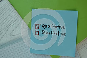 Qualitative and Quantitative write on sticky notes and supported by additional services isolated on Wooden Table