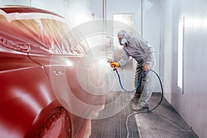 Quality auto body shop concept. Painting the car in red color in the paint chamber on the service.