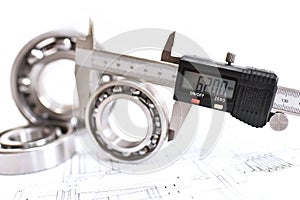 Quality control in modern mechanical engineering - caliper gauges, technical drawing and ball bearings on white background