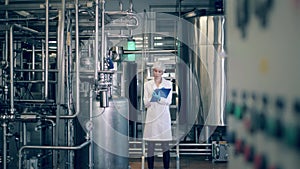 Quality control of production line at a factory. A person checks metal tanks at a dairy factory.